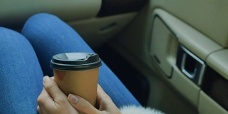 女孩拿着一杯咖啡坐在车里