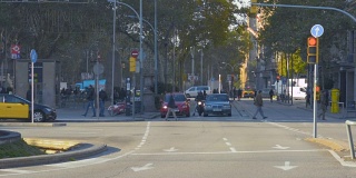 西班牙巴塞罗那，清晨忙碌的人们走在穿过格拉西亚大道的人行横道上。