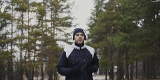 迷人的跑步者戴着耳机在冬天的早晨听着音乐慢跑