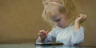 慢镜头:一个三岁的小女孩在家里用智能手机在网上选了一幅漫画。