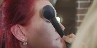 化妆师在模特脸上涂抹遮瑕膏。
