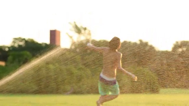 一个小男孩在草坪上玩，慢镜头60fps, 4k分辨率。无拘无束的婴儿享受生命中的小事物，在夕阳的黄金时刻，在绿色田野的理想时刻