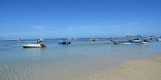 蓝天和蜻蜓船在海滩上。亚洲印尼巴厘岛Sanur海滩上的Jukung渔船