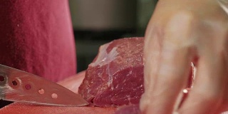 厨师用刀在红板上切生肉，特写慢动作