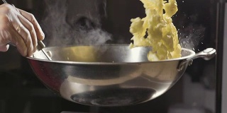 厨师在钢锅里煎蛋卷，特写慢动作。