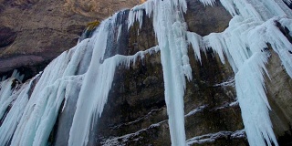 高冻结瀑布与冰在蓝色和白色的颜色在冬天
