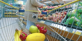 推着手推车在超市买新鲜蔬菜和水果的妇女