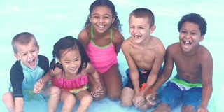 五个多民族的孩子在游泳池里大笑