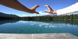 一对夫妇的手在湖边做了一个心形的框架