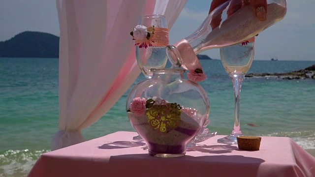 The bride pours sand into the vase. Wedding decoration near the sea.