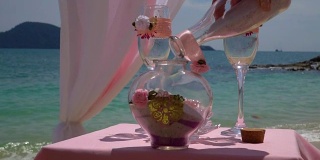 The bride pours sand into the vase. Wedding decoration near the sea.