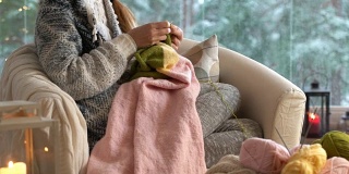年轻女子在客厅里织着温暖的羊毛衫，窗外是雪景