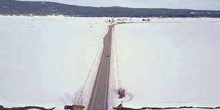 空中4K:一辆汽车在高速公路上穿越白雪覆盖的田野