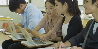 亚洲大学生正在课堂上讨论和使用笔记本电脑