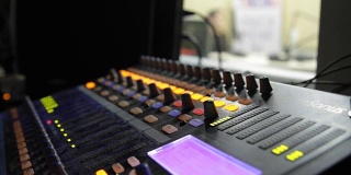 专业音频操作员在电视直播期间对音频混音旋钮进行操作。