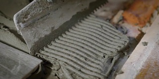 在用抹刀平整水泥的过程中，工头手里拿着一个工具，引导他们穿过水泥