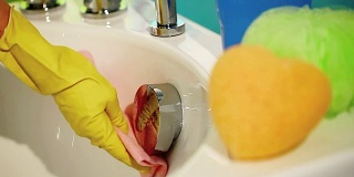 手戴手套，用抹布擦拭浴缸，打扫浴室
