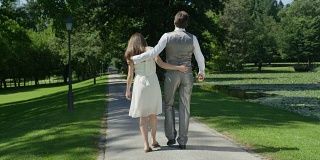 慢镜头:在绿色的公园里平静地散步时，父母被拥抱着
