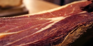 Jamon塞拉诺。传统西班牙火腿在市场上收市。桌上的猪腿火腿。餐厅内部的美食肉。整个火腿放在架子上。多莉
