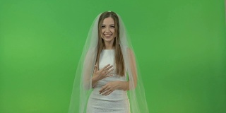 年轻的白人女孩穿着新娘礼服，在绿色的背景上。