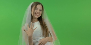 年轻的白人女孩穿着新娘礼服，在绿色的背景上。她手指上戴着一枚订婚戒指