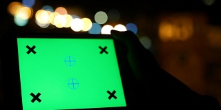 使用绿色屏幕的数字平板电脑与夜间交通灯背景的特写镜头