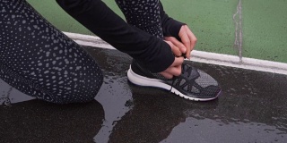 女人系鞋带的特写。准备慢跑的女性运动健身运动员