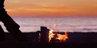 剪影人放置在海滩篝火上的原木