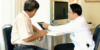 亚洲医生用平板电脑向资深男病人解释
