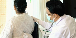 年轻医生用听诊器在女病人的背上听诊