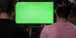 几个令人不寒而栗的家伙在沙发上用彩色键绿色电视屏幕上的手柄玩视频游戏