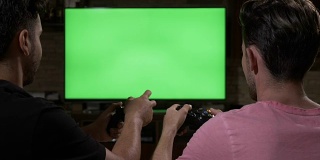 年轻的朋友有乐趣与无线操纵杆相互竞争，在色度键绿色屏幕上玩视频游戏