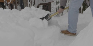 在一个大雪纷飞的寒冷早晨，一名男子拿着铲子正在清除院子里的积雪，