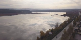 以湖泊为背景，无人机拍摄高速公路上行驶的卡车和汽车