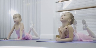 两个女孩躺在垫子上，做伸展运动来发育脊椎