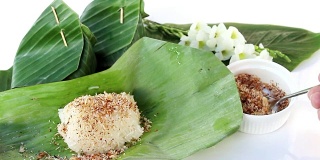 泰式甜点:糯米鱼干，香蕉叶包裹，白色背景。