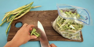 女人的手切豌豆，放进塑料袋冷冻。冷冻蔬菜