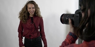 一名年轻漂亮的女学生模特对着数码相机旋转和微笑的慢镜头拍摄了一本女性封面杂志