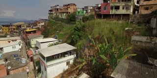 贫民窟航拍:特写角度飞上和飞越山顶贫民窟，揭示背后的沿海城镇安格拉dos Reis