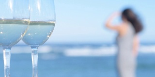 以大海为背景的两杯白葡萄酒。