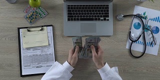 俯视图的医疗工作者计算许多美元钞票，昂贵的医疗保健