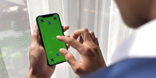 商人看智能手机与绿色屏幕手持智能手机，iPhone X
