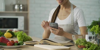 在智能手机上看烹饪书计算卡路里的漂亮女人