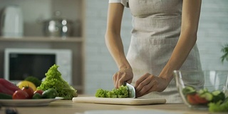 女孩切好沙拉叶子，放进玻璃碗里，这是健康的生活方式，饮食