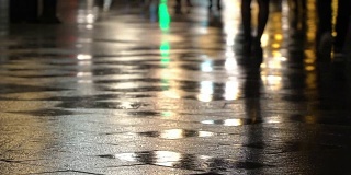 在潮湿的人行道上，街灯映出了辨认不出的人的剪影。长长的影子。雨夜的城市街道上有路灯，沥青路从雨中闪闪发光。不认识的行人，年轻人。夜晚的城市下雨。购物的概念