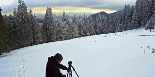 在冬季山区，摄影师带着三脚架上的相机