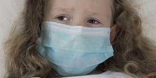 重病女孩子戴着医用口罩，惊恐地看着注射器