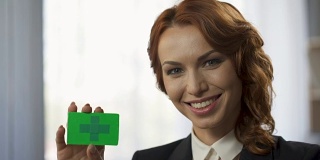 微笑的少妇手里拿着绿色的彩卡，全新便捷的服务