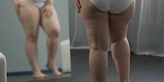 有体重问题的女孩在镜子里看着自己的腿，用手抚摸它们