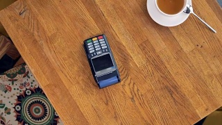 在NFC支付过程中从上面看到的咖啡杯和智能手机。视频素材模板下载